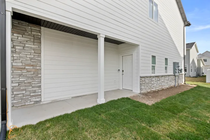 Covered patio area featuring a concrete slab and a white paneled entry door