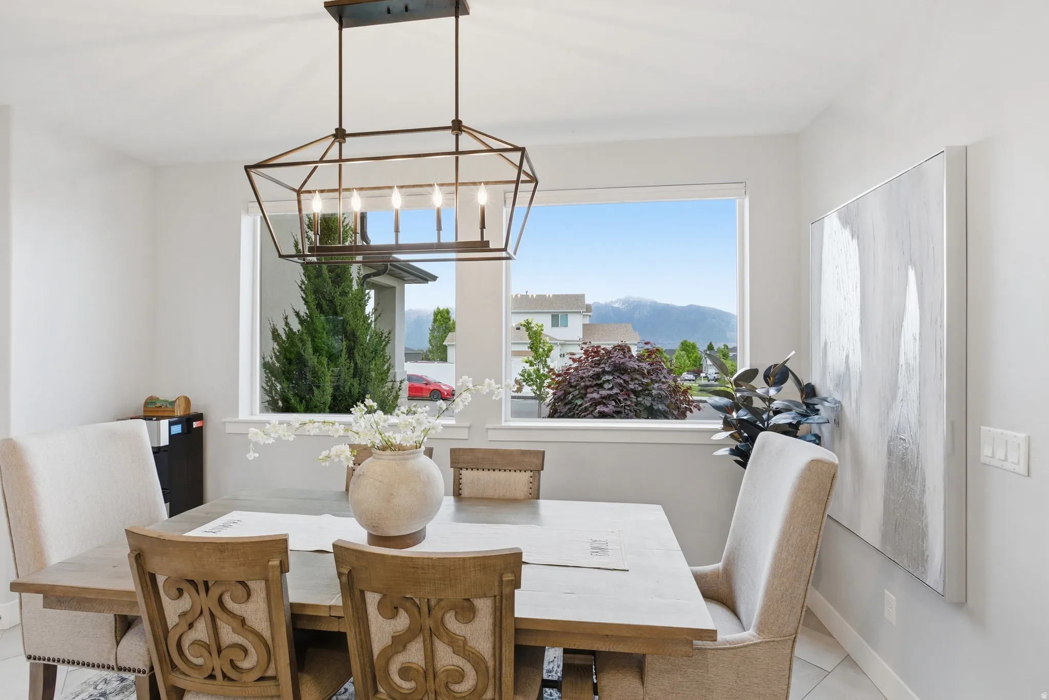 Dining area featuring a contemporary linear chandelier, large picture windows, and light-toned walls