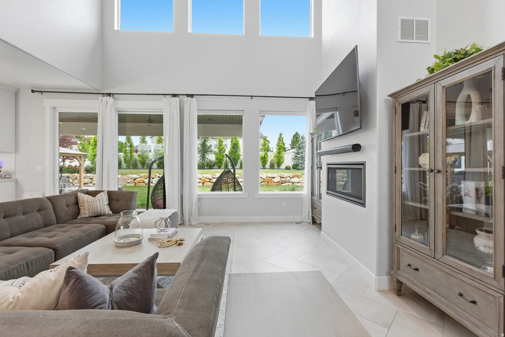 Living area featuring a double-height ceiling, large transom windows, and expansive glass doors opening to the exterior