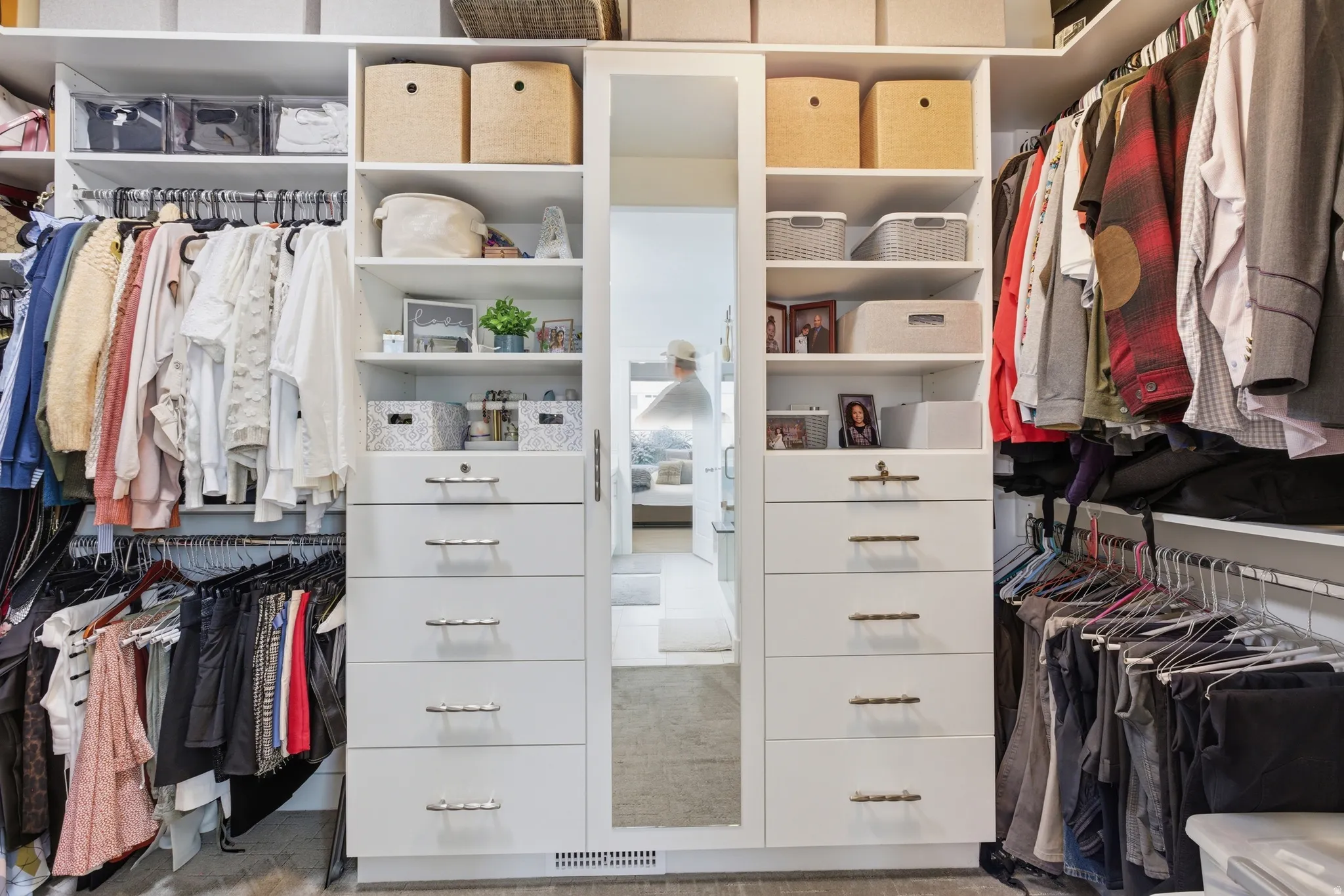Custom closet system featuring built-in white cabinetry, integrated shelving, multiple hanging rods, ample drawer storage, and a full-length mirrored door