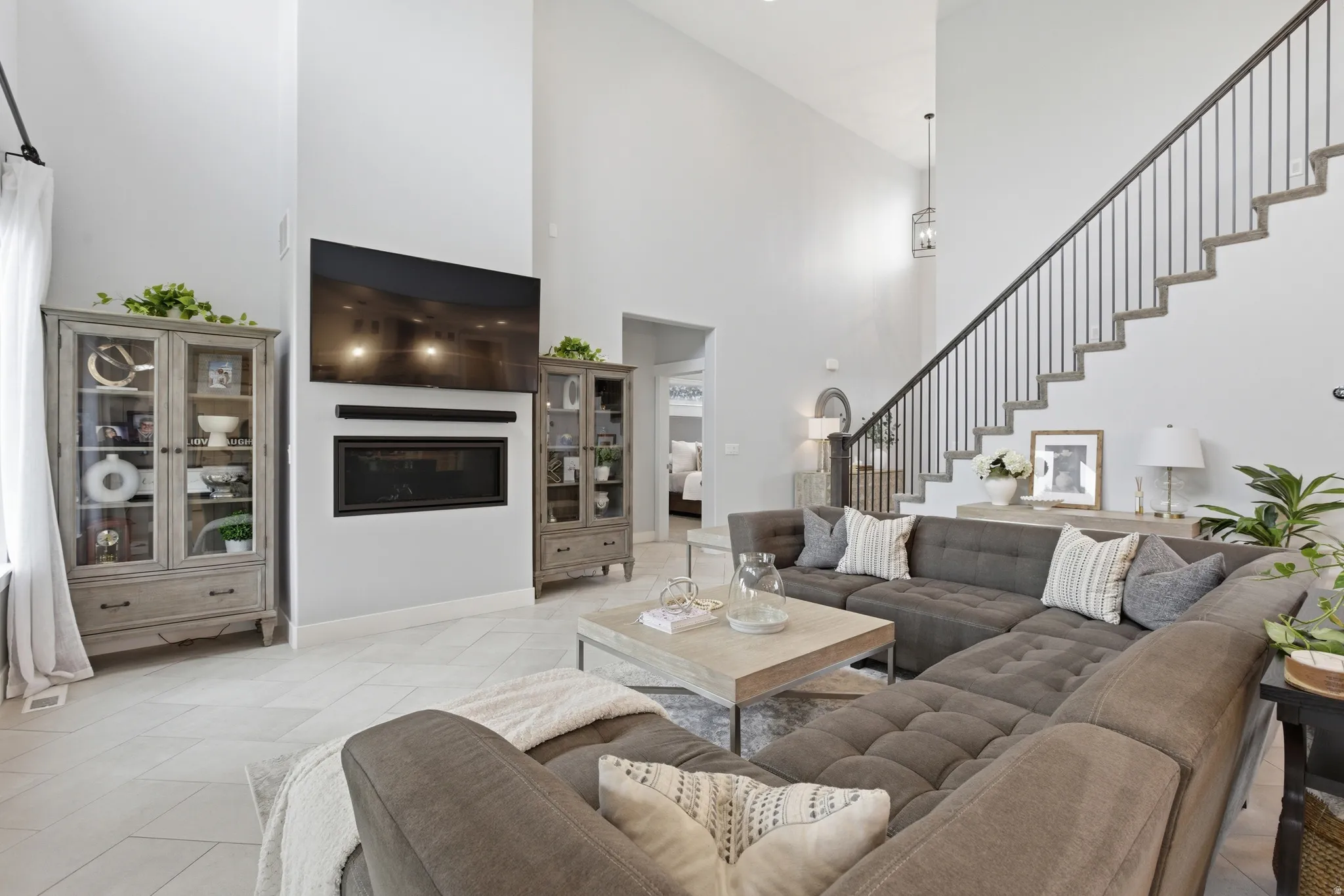 Expansive living room featuring vaulted ceilings, a contemporary fireplace, and a striking staircase with iron balusters
