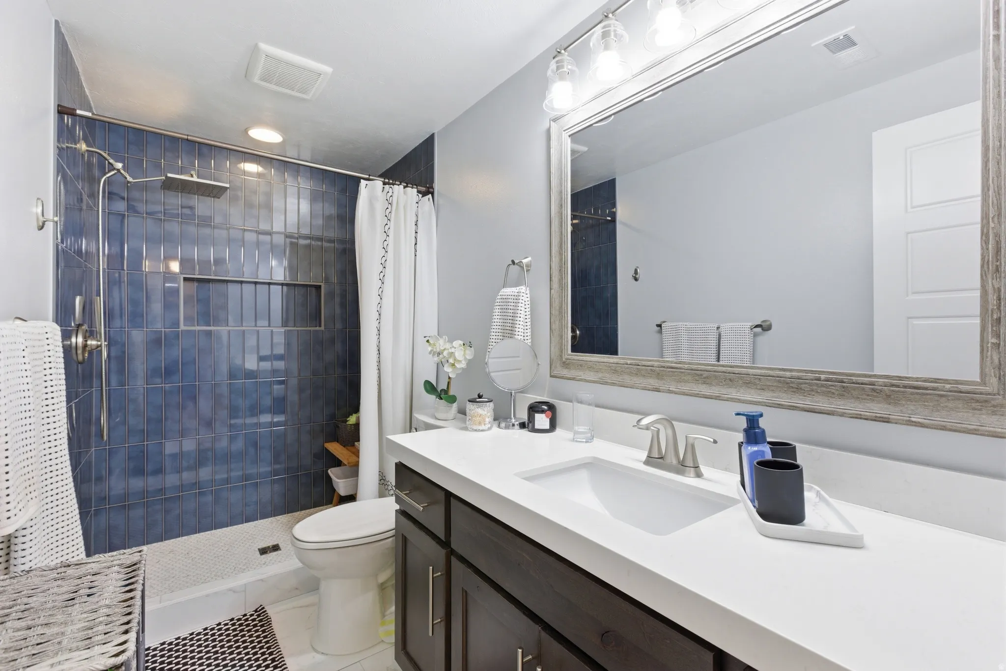 Bathroom featuring a walk-in shower with blue subway tile, a shower niche, and a rainfall showerhead
