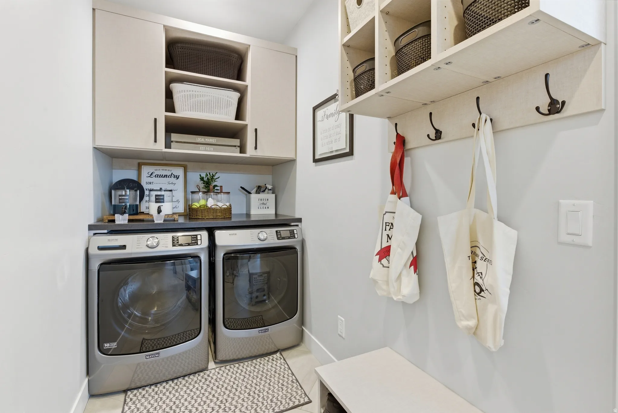 Dedicated laundry area featuring a side-by-side washer and dryer, dark countertop, and light cabinetry