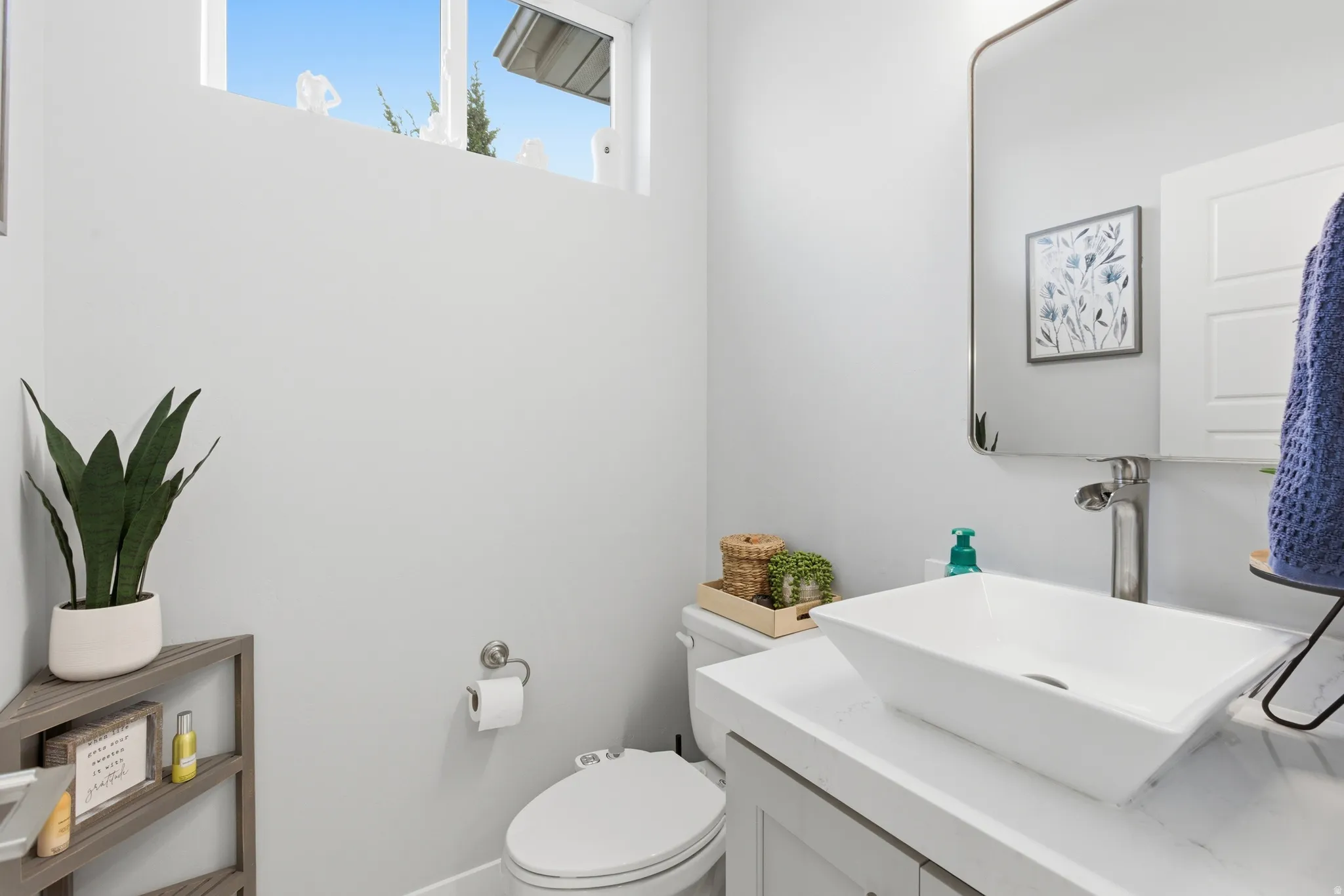 Contemporary powder room featuring a vessel sink, single-handle faucet, and white vanity with stone-finish countertop