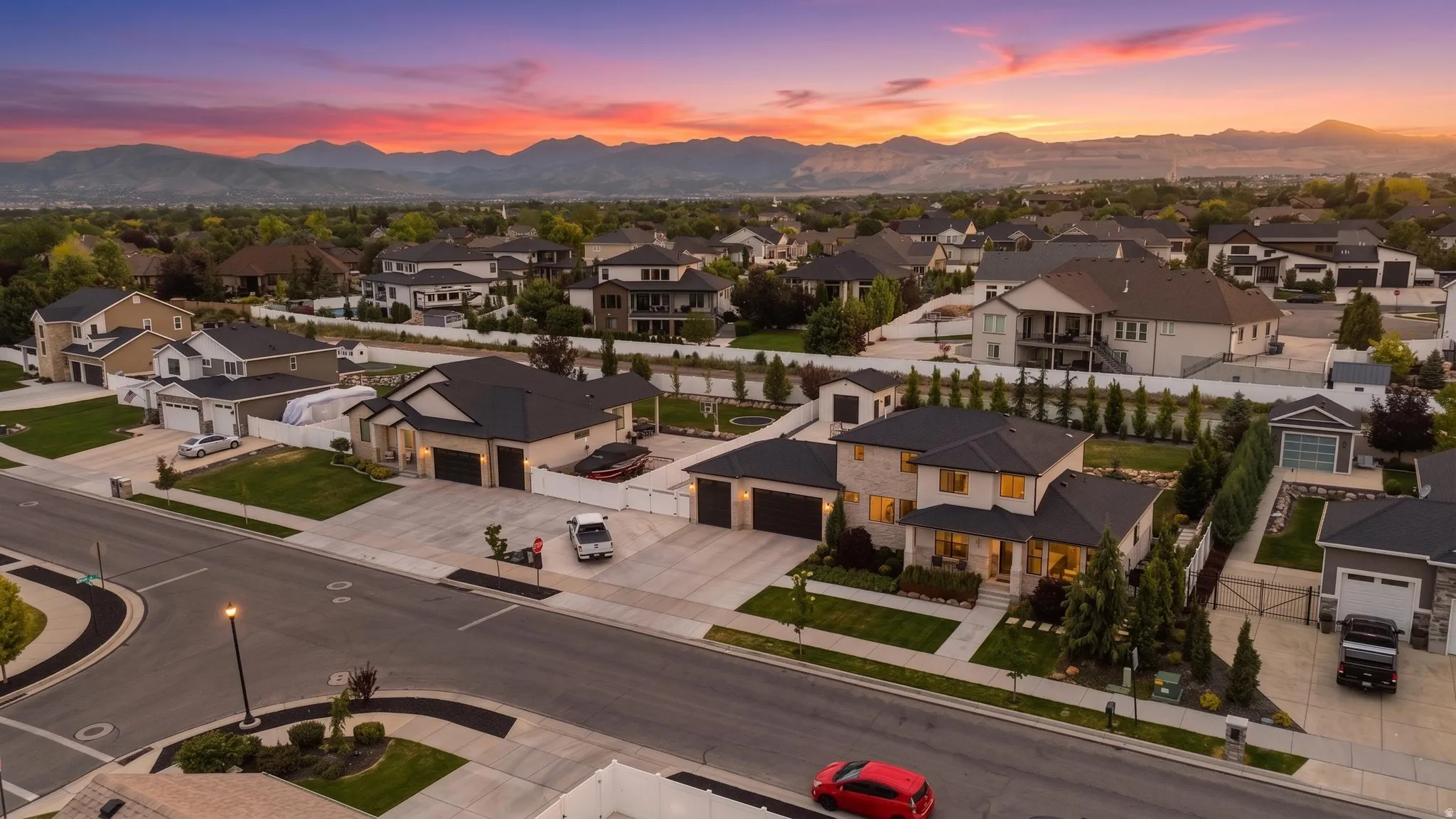 Two-story residence featuring a stone and stucco exterior, multiple garage bays, covered entry porch, and mature front landscaping
