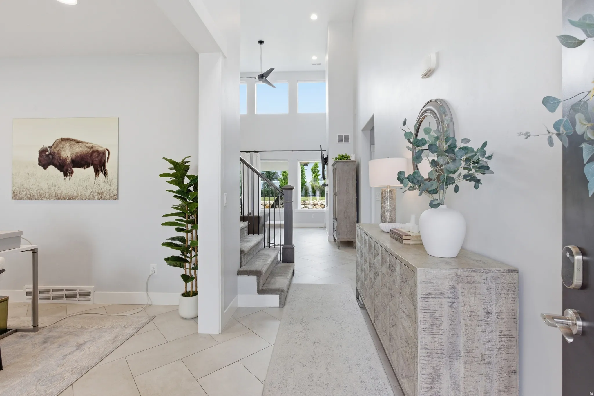 Entryway featuring high ceilings, a contemporary staircase with dark railings, recessed lighting, and light tile flooring