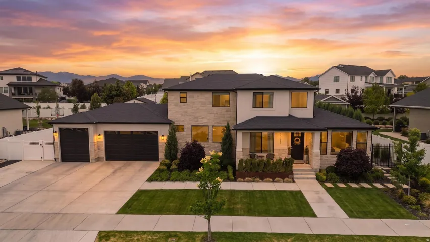 Modern two-story residence featuring a stone and stucco exterior, an attached three-car garage, and a covered porch