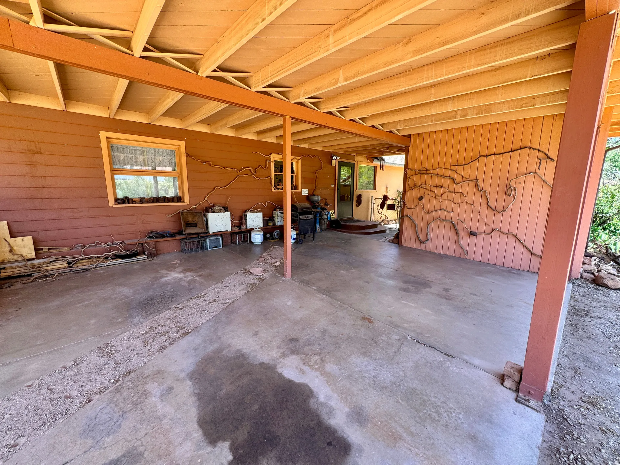 Covered outdoor patio with exposed beam ceiling and concrete flooring