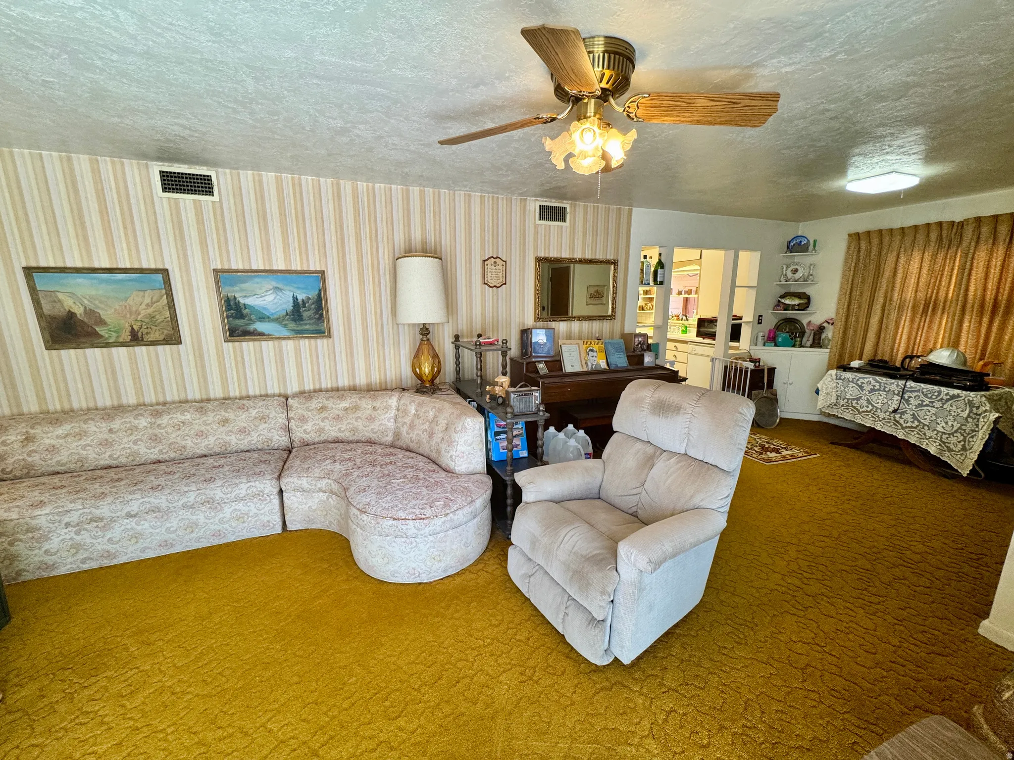 Living space featuring textured gold carpeting and striped wallpaper