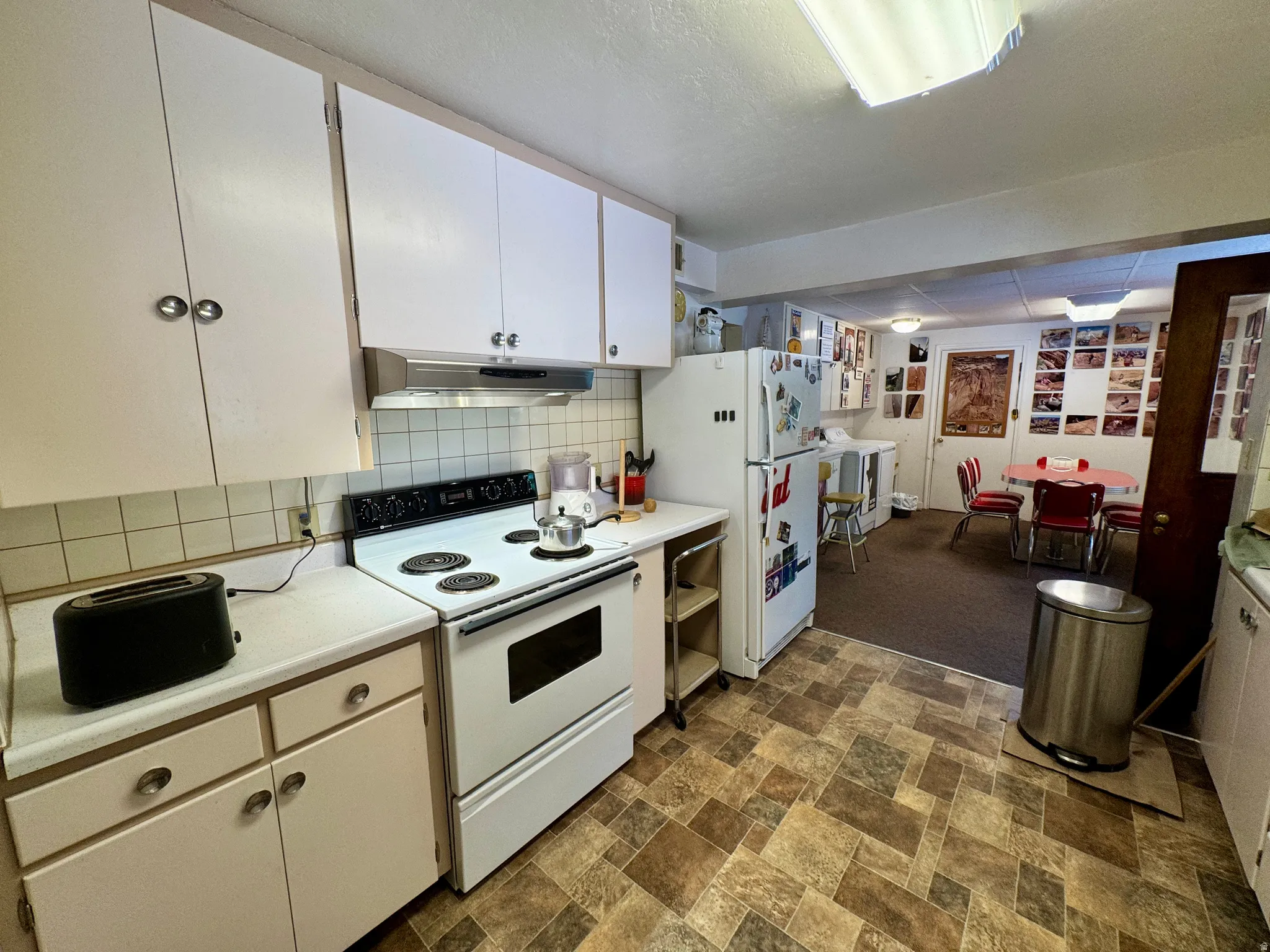 Functional kitchen featuring white cabinetry, a white electric range, and a rectangular tile backsplash