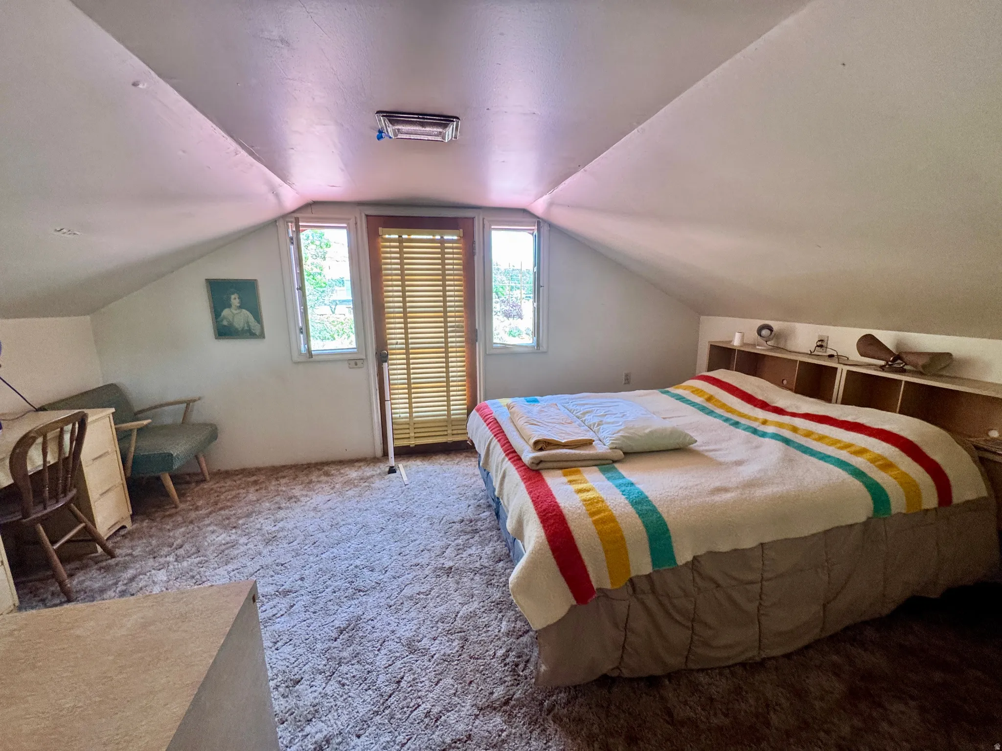 Attic room featuring sloped ceilings, light-colored wall surfaces, and a built-in headboard with integrated shelving