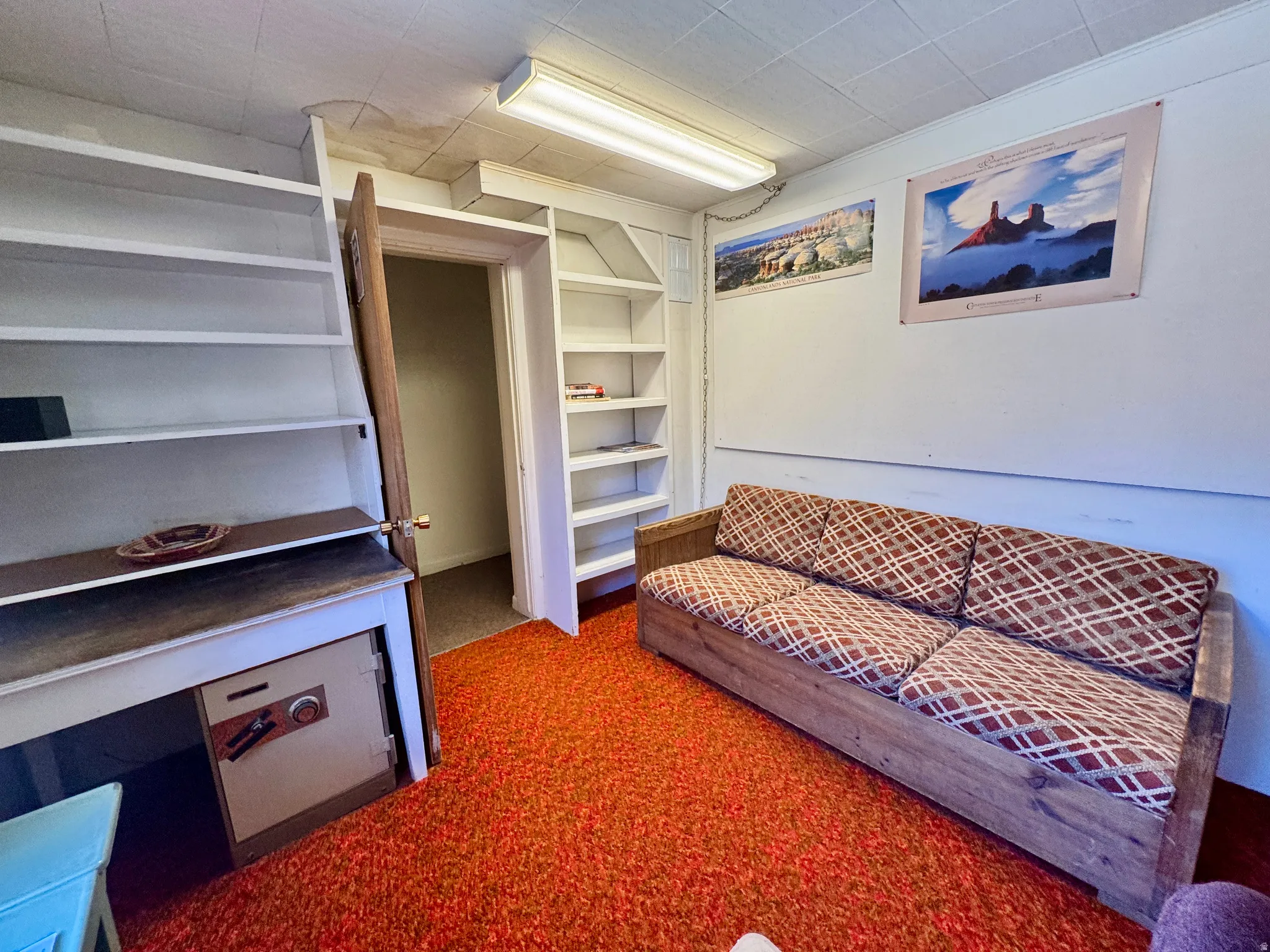 Room featuring built-in shelving, an additional built-in bookshelf, a fluorescent ceiling light fixture, and textured ceiling panels