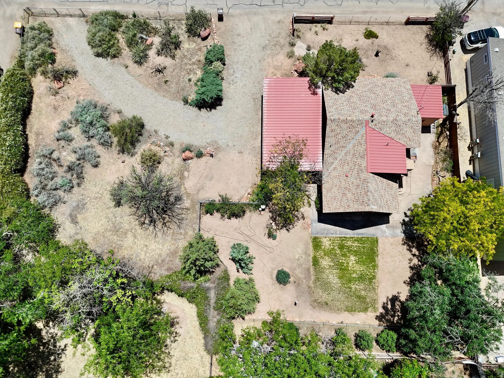 Property featuring a red metal roof section, a shingled roof section, and a gravel driveway