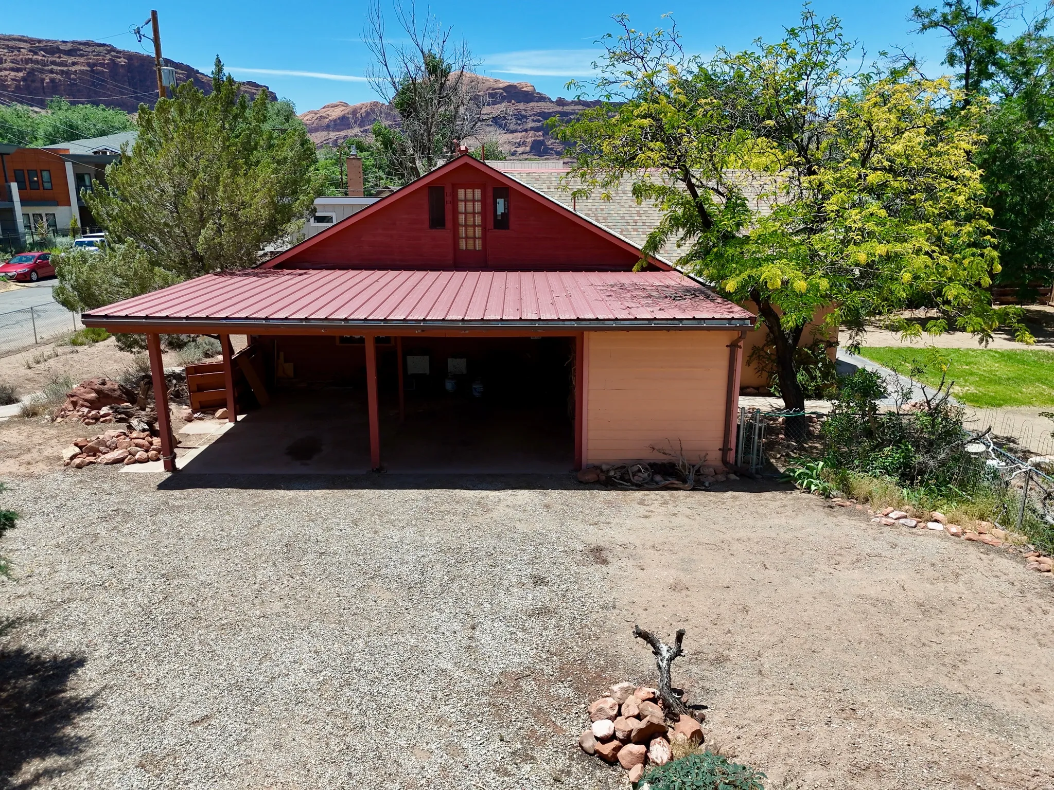 Red-painted exterior featuring a metal roof and a covered carport with exposed wood beams