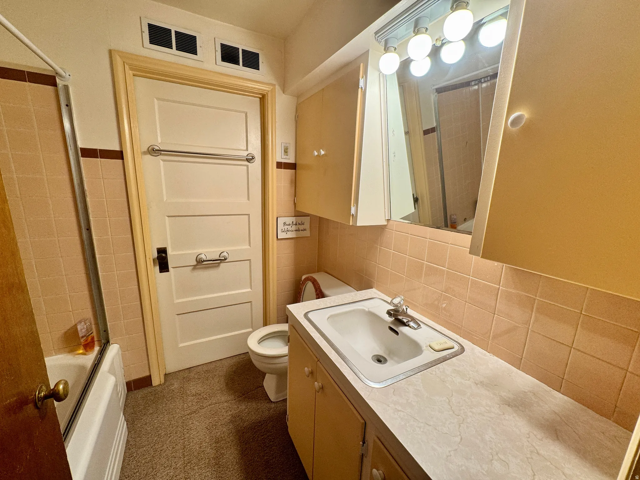 Bathroom featuring a built-in vanity with laminate countertop, integrated sink, and medicine cabinet with vanity lighting