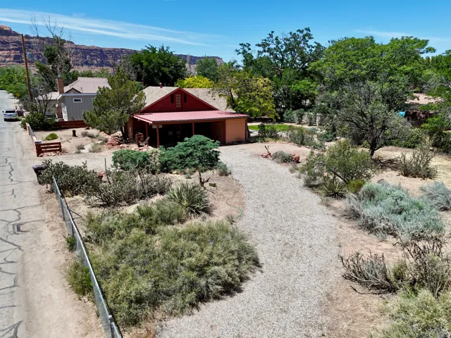Red-roofed residence with an attached carport, gravel driveway, and surrounding desert landscaping