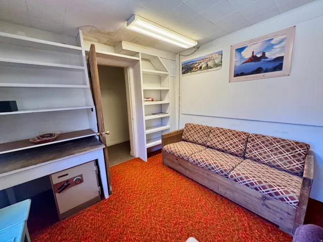 Room featuring built-in shelving, an additional built-in bookshelf, a fluorescent ceiling light fixture, and textured ceiling panels