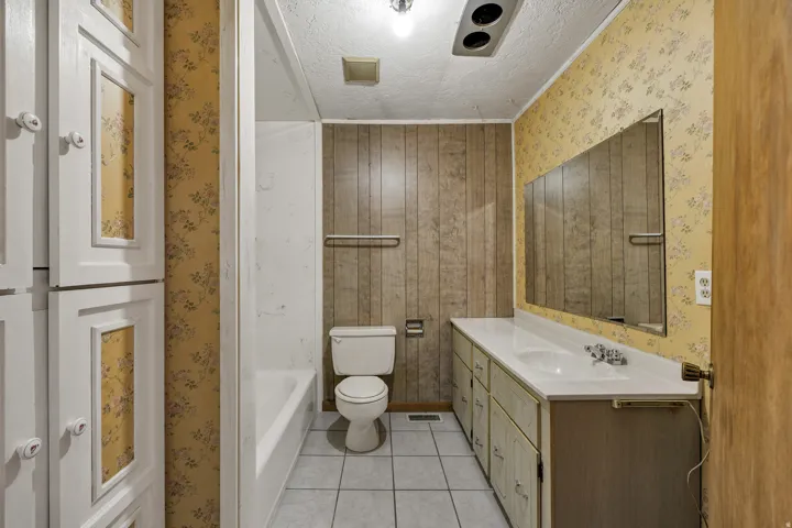 Bathroom featuring a single vanity with dual basins, white countertop, and expansive mirror