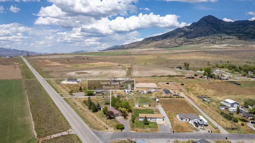 Expansive rural property featuring a prominent mountain backdrop and a long paved road
