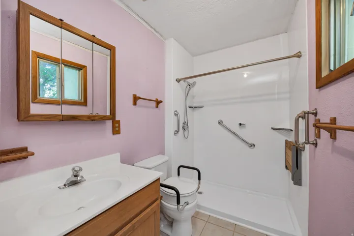 Bathroom featuring a single vanity with a laminate countertop, an integrated sink, and wood cabinetry
