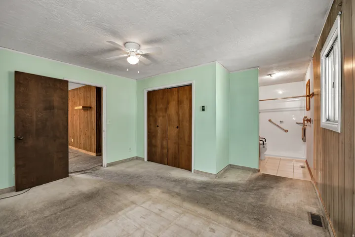 Spacious room featuring light green walls, a ceiling fan, and carpeted flooring