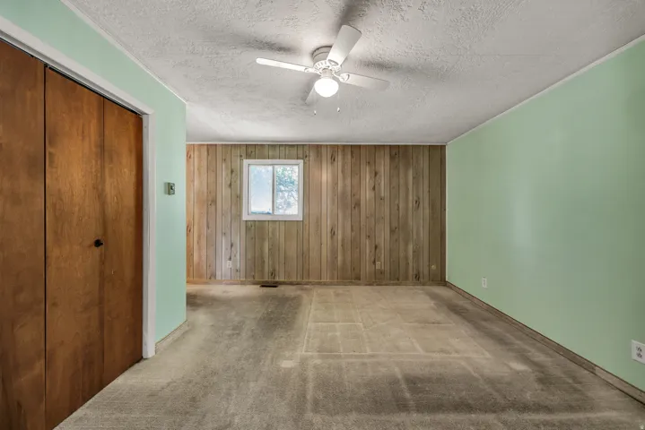 Interior room featuring wood paneling, a single window, and light green painted walls