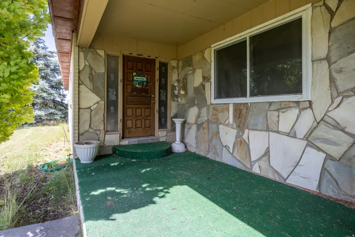 Stone veneer facade with a covered porch featuring green outdoor carpeting