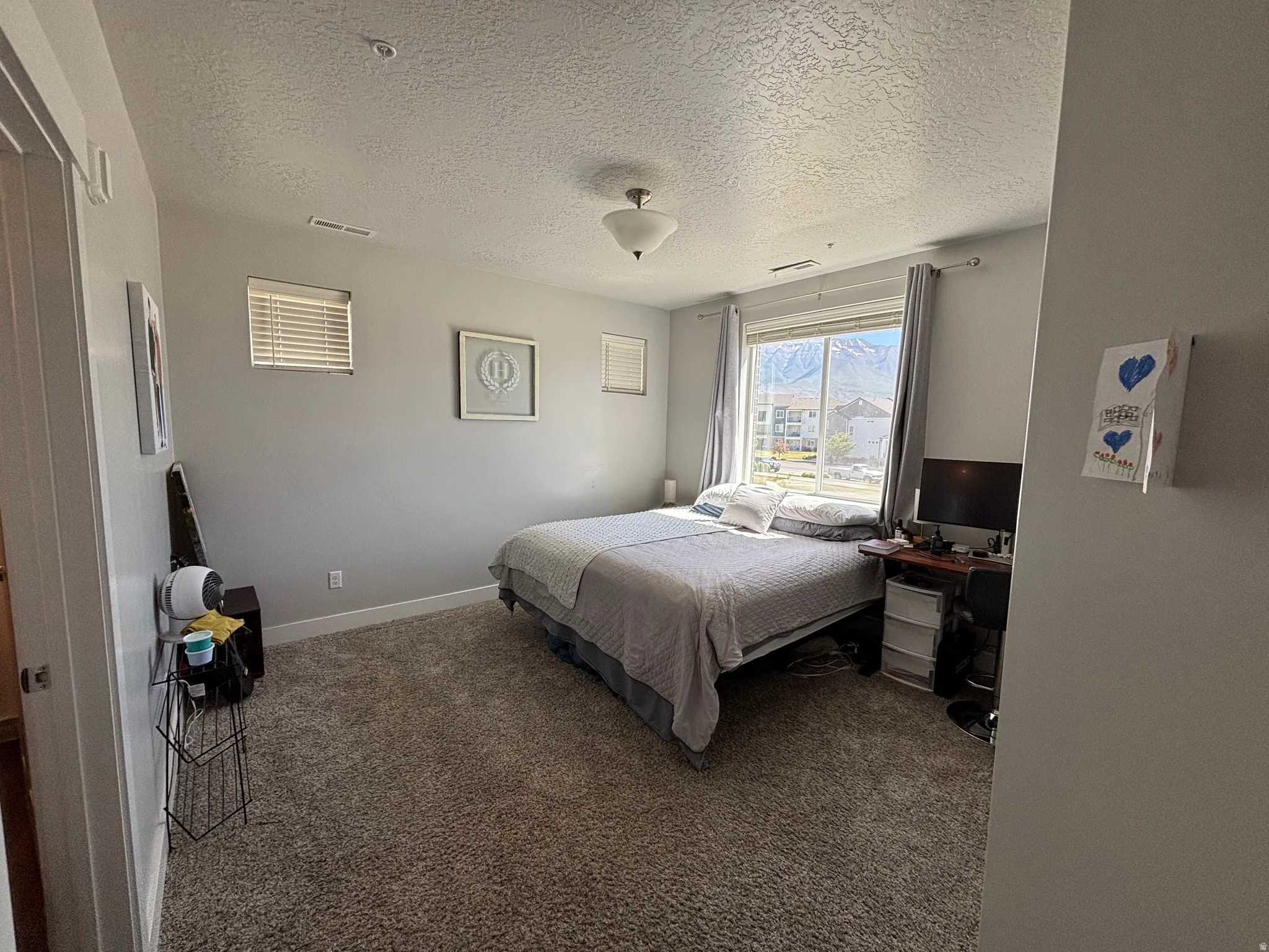 Carpeted room featuring light gray walls and a large window with a distant mountain backdrop