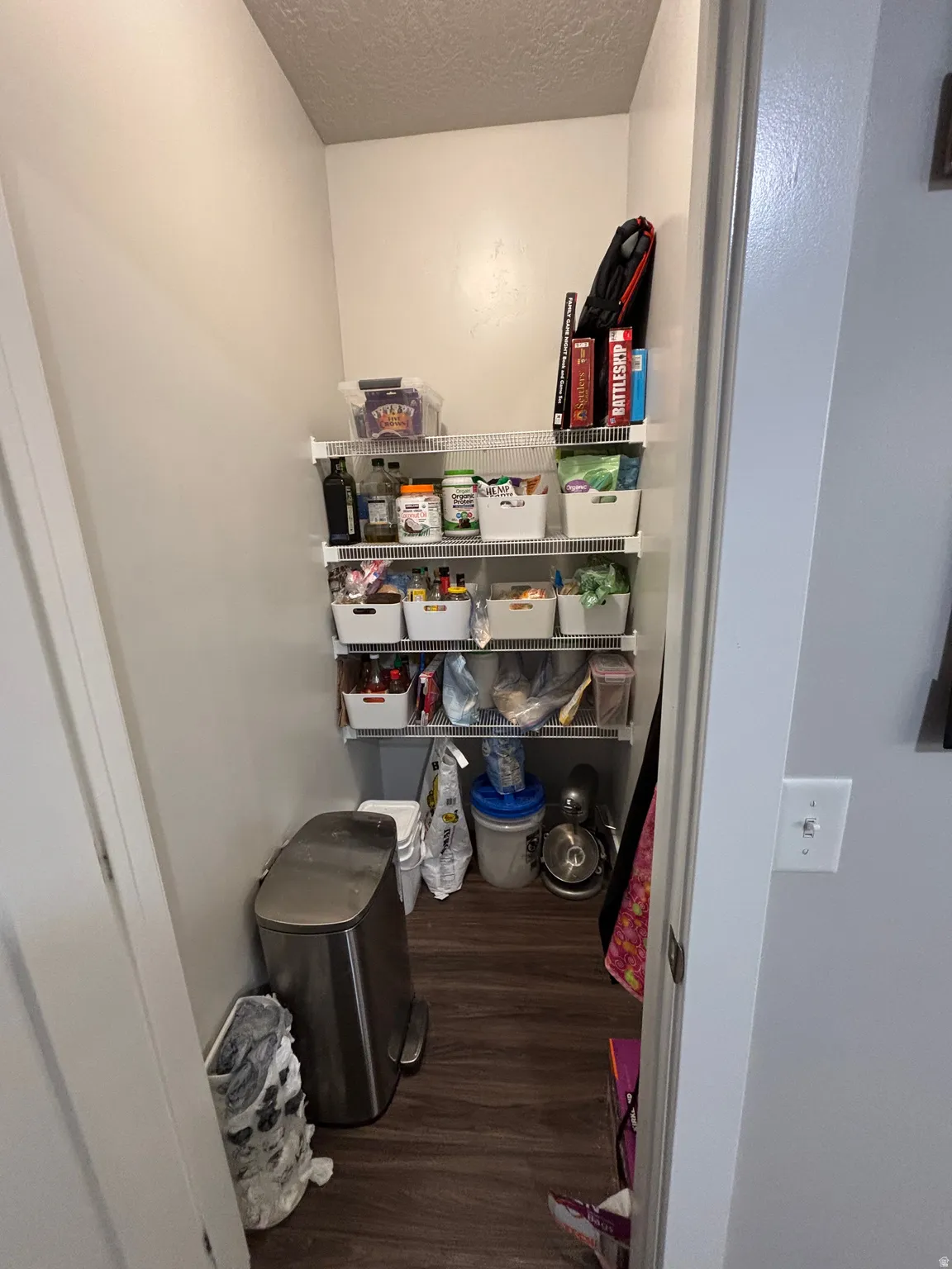 Pantry with wood-finish flooring and multiple levels of wire shelving