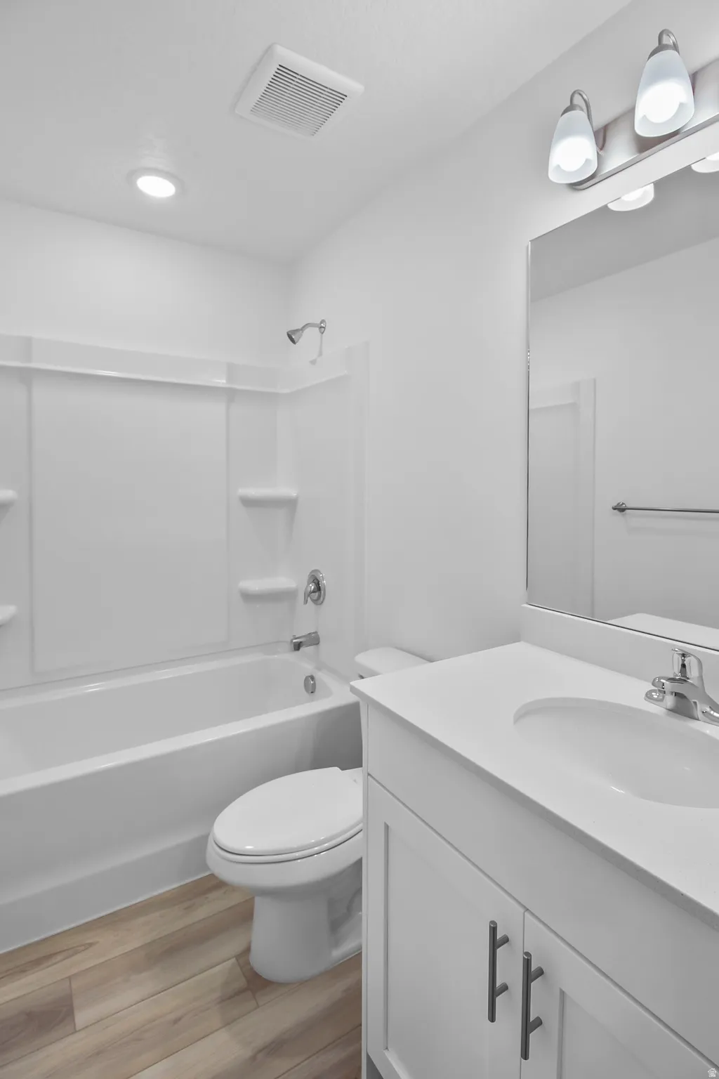 Bathroom featuring a white vanity with an integrated sink, polished chrome faucet, and a large wall-mounted mirror