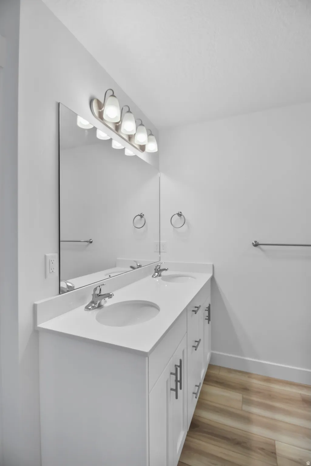 White dual vanity with integrated sinks, brushed nickel faucets, and a coordinating mirror with a six-light vanity fixture