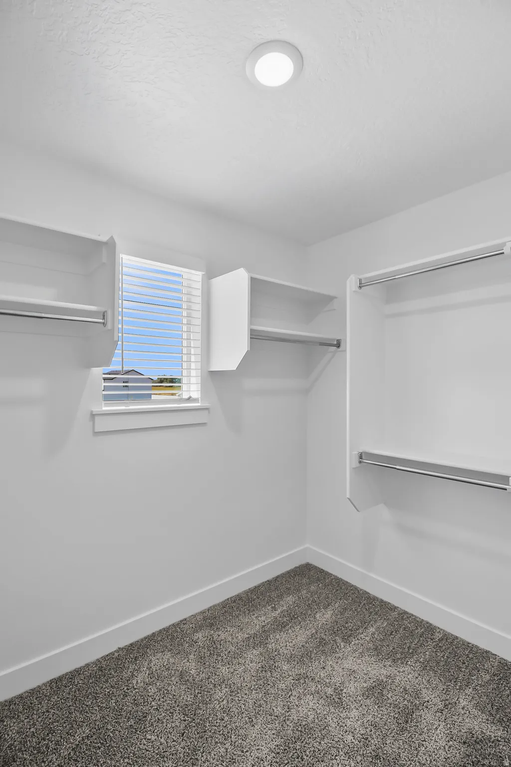 Walk-in closet featuring built-in shelving, hanging rods, recessed ceiling lighting, and a window with blinds