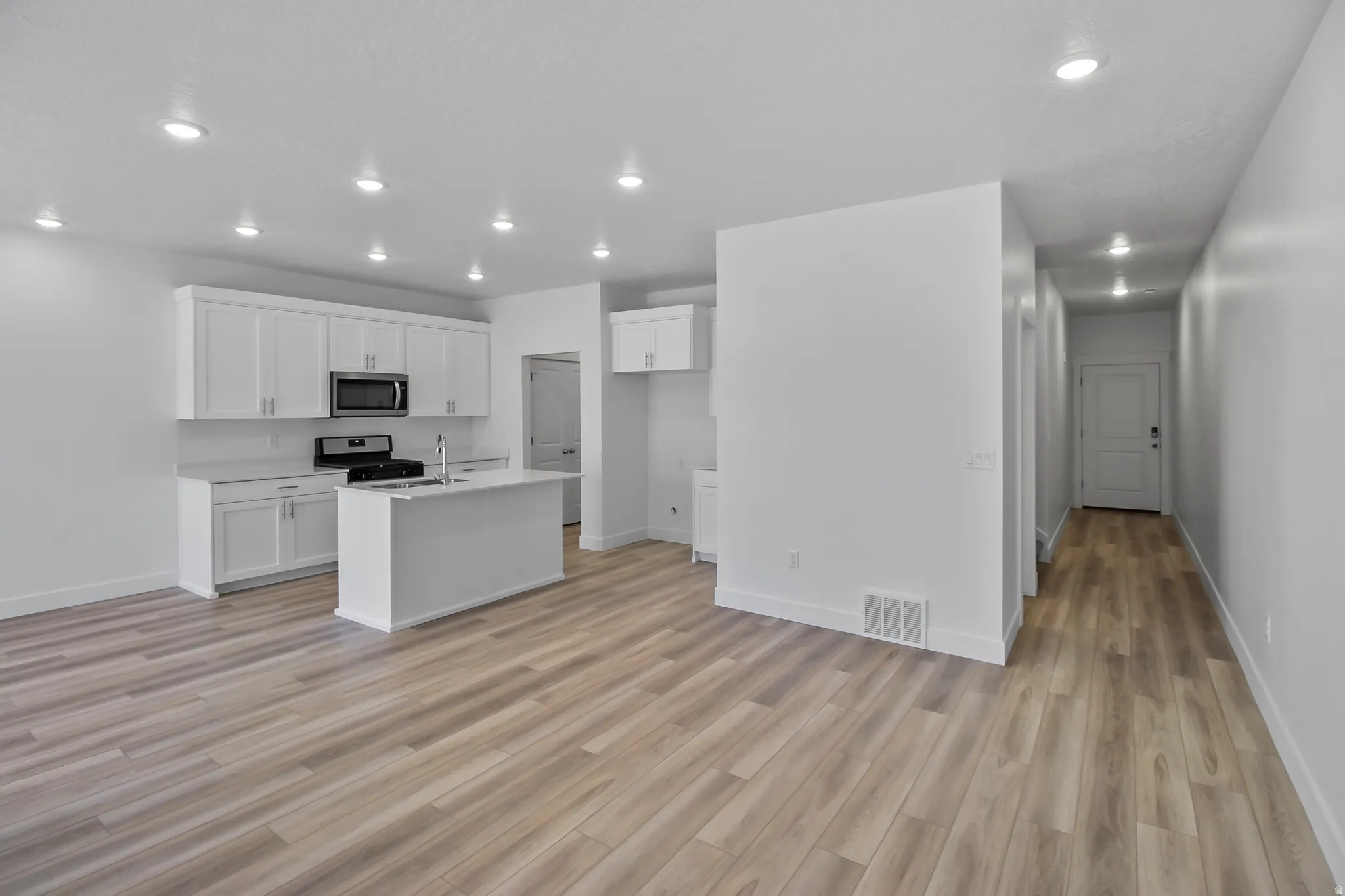 Open-concept living space featuring wood-finish flooring, recessed lighting, and white baseboards