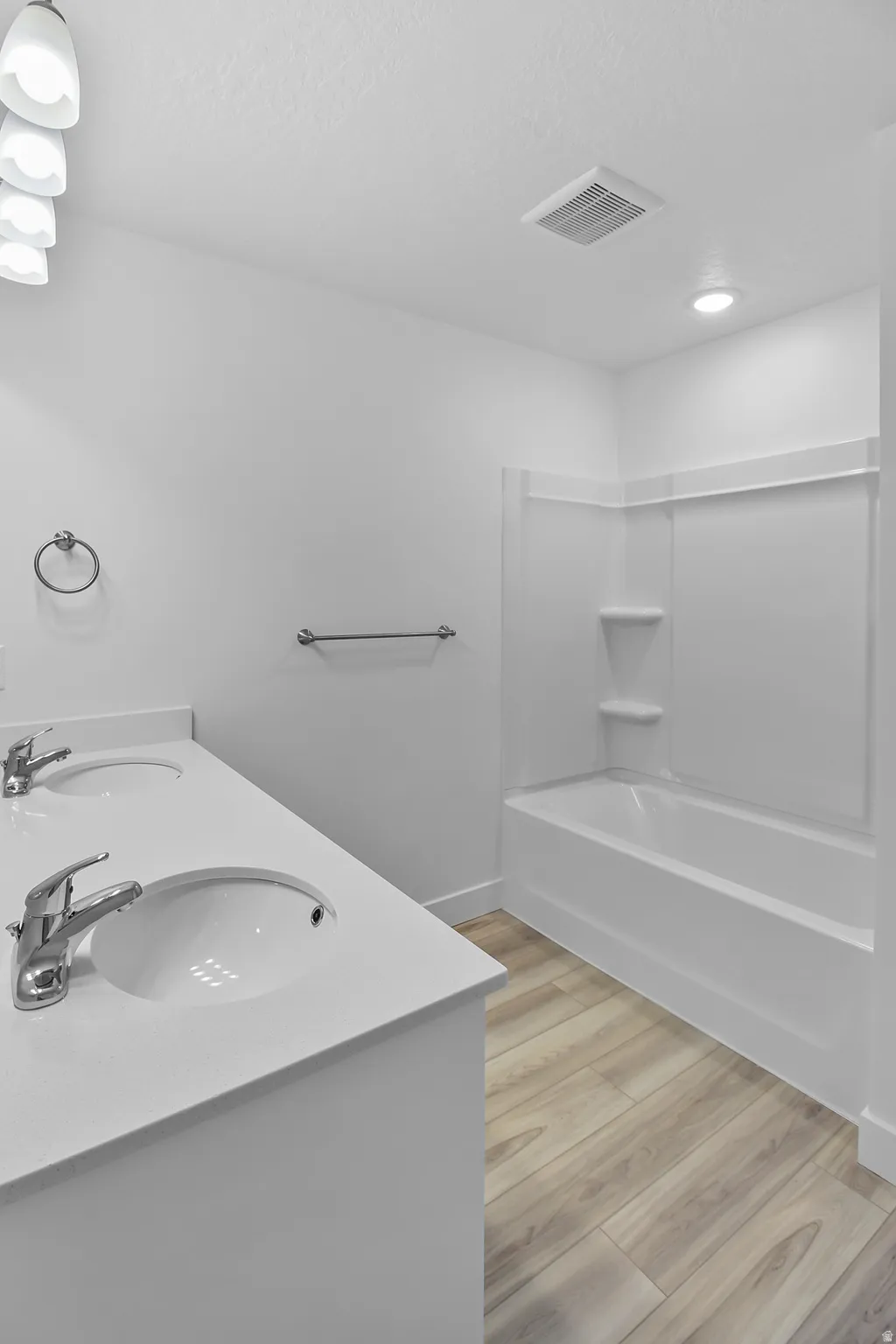 Bathroom with dual basin vanity featuring white countertops, undermount sinks, and chrome faucets