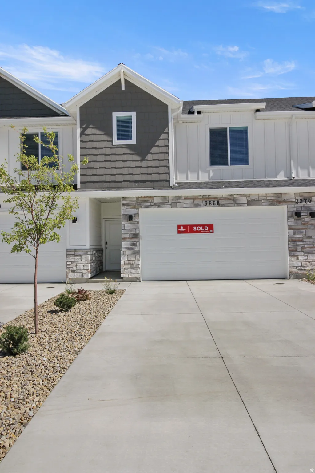 Contemporary townhome exterior featuring light-toned stone veneer accents and dark shake siding