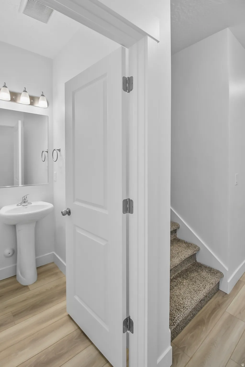 Pedestal sink vanity with a mirror and brushed nickel vanity lighting
