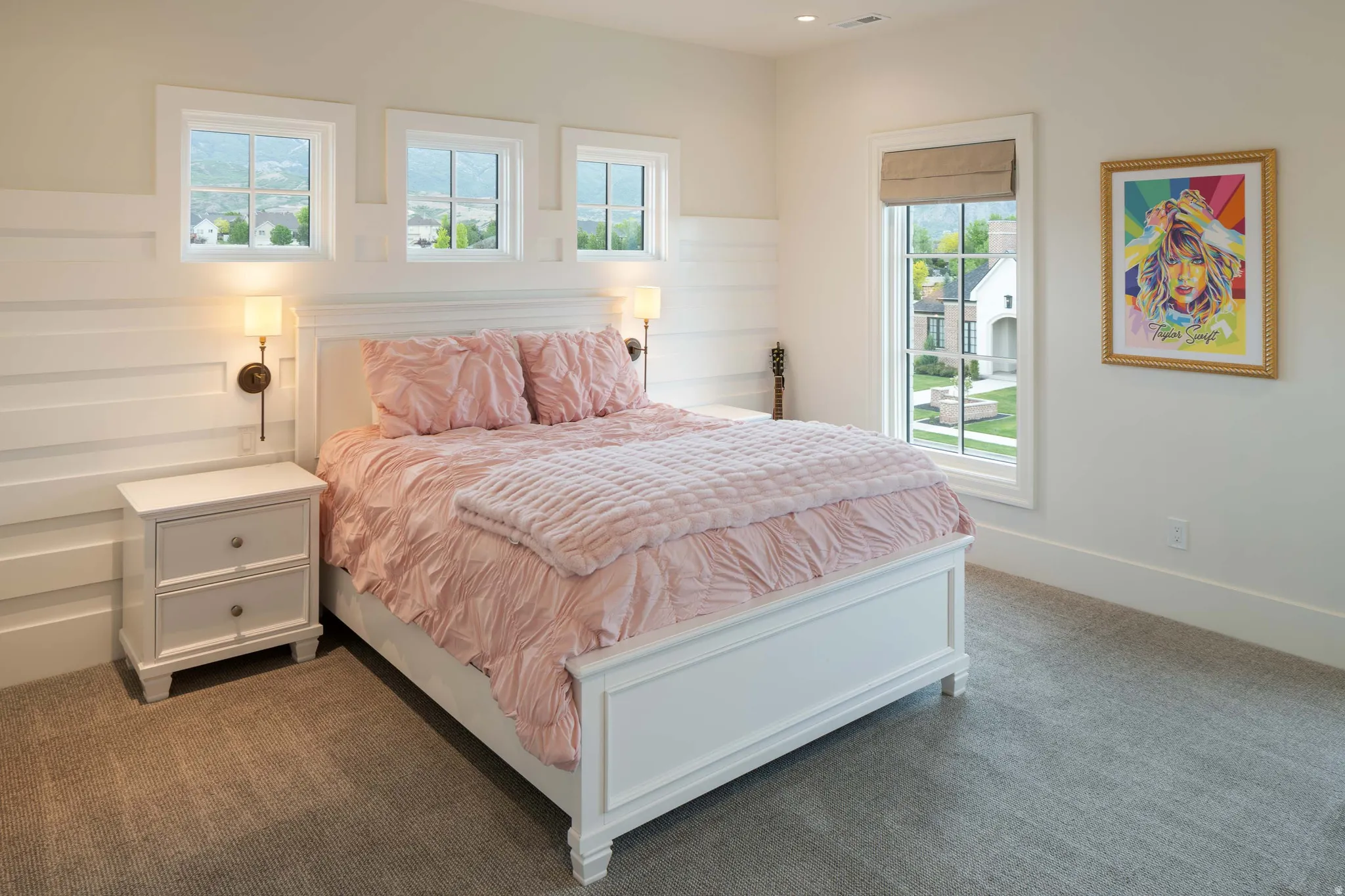 Bedroom featuring broadloom carpet, white shiplap accent wall, white framed windows, and built-in wall sconces