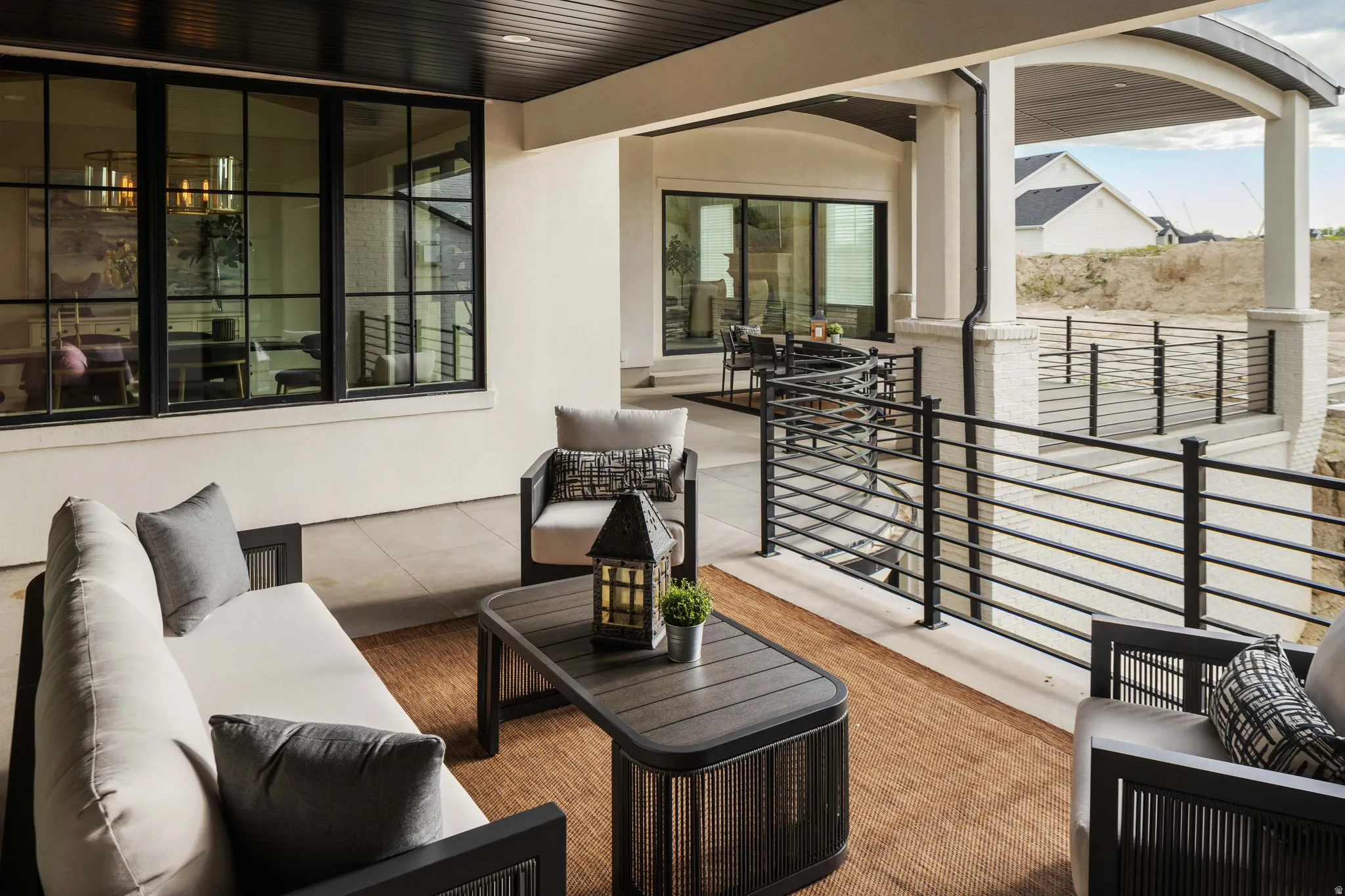 Covered outdoor patio featuring a slatted dark wood ceiling, white stucco walls, and a concrete floor