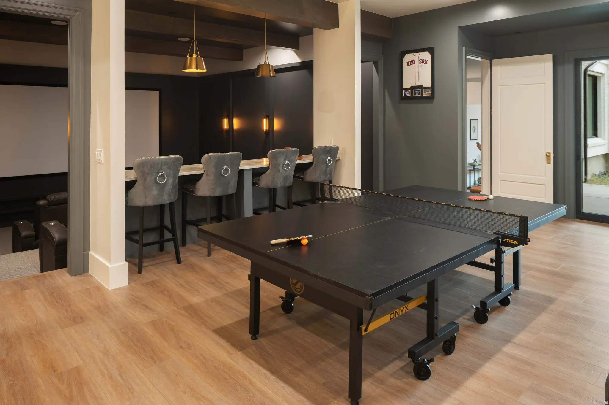 Open-concept recreation area featuring wood-finish flooring, a built-in bar with pendant lighting, and recessed ceiling lighting