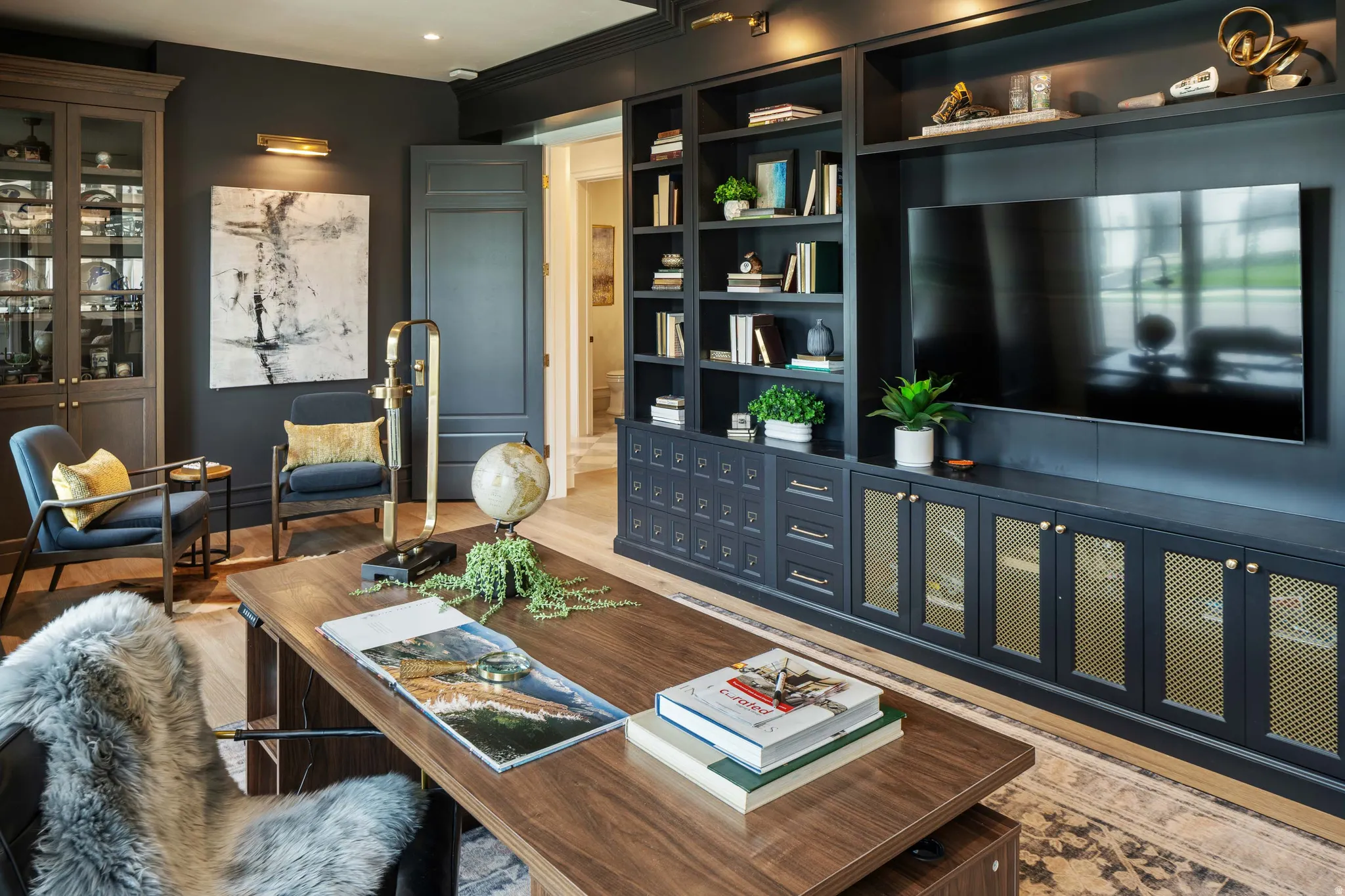 Custom built-in shelving with integrated television, shaker panel doors, and brass mesh accents