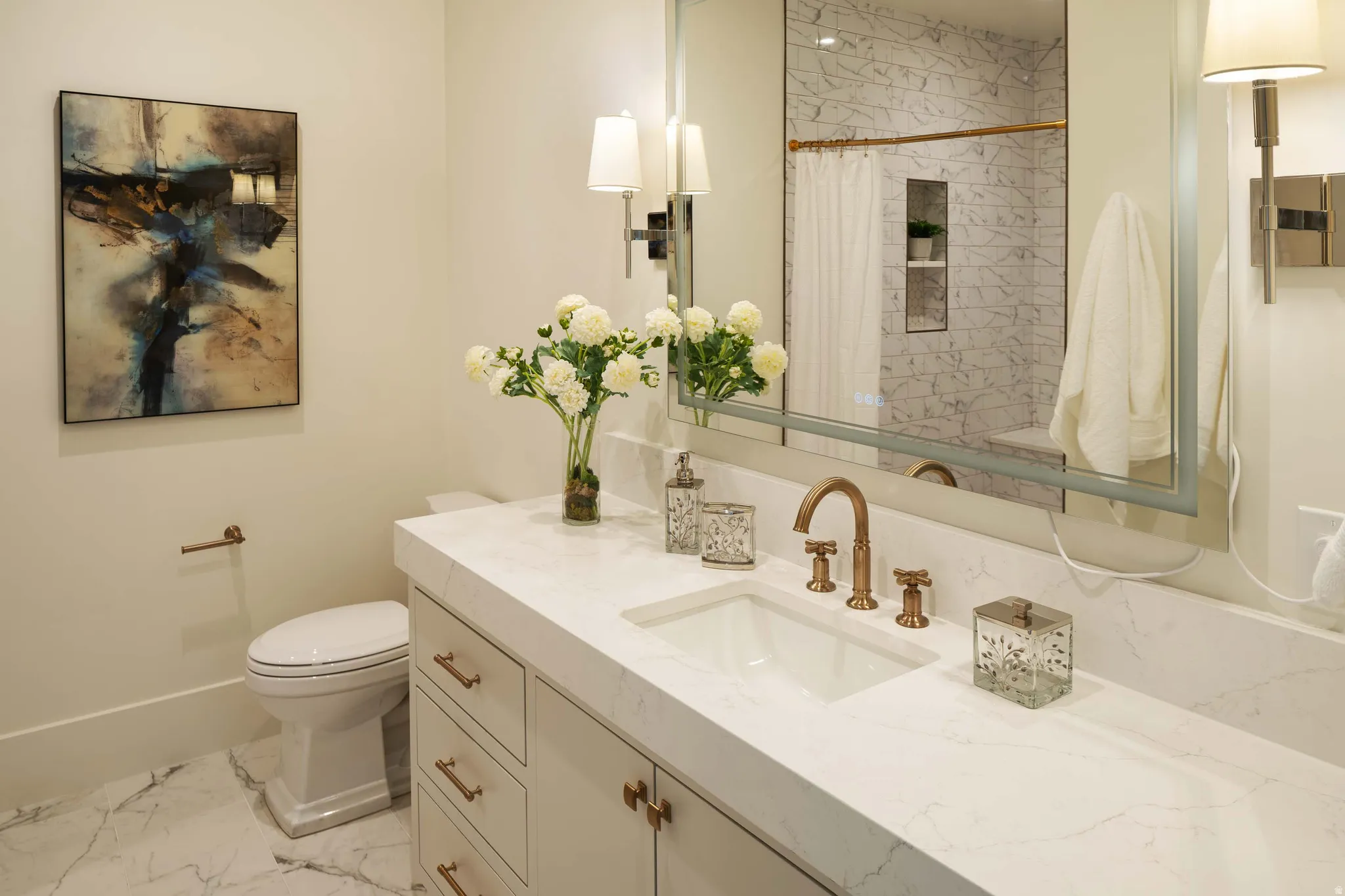 Vanity with a white countertop and integrated sink, complemented by a bronze-toned faucet