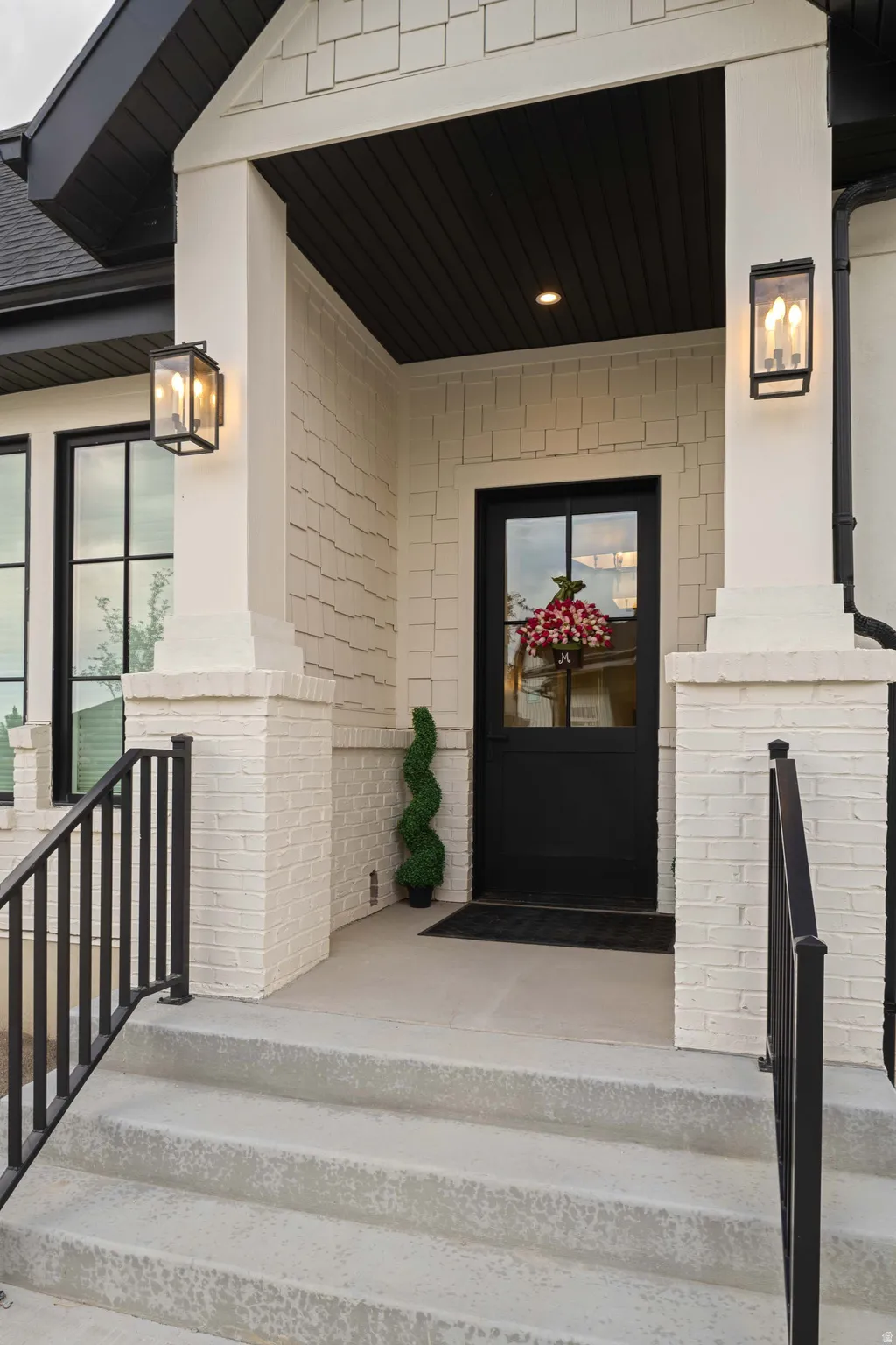 Inviting front entry featuring a glass-paneled door, black-framed windows, and two external sconces