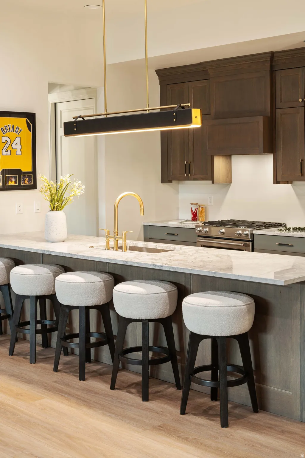 Kitchen island with stone countertop, integrated sink, and gold-finish faucet