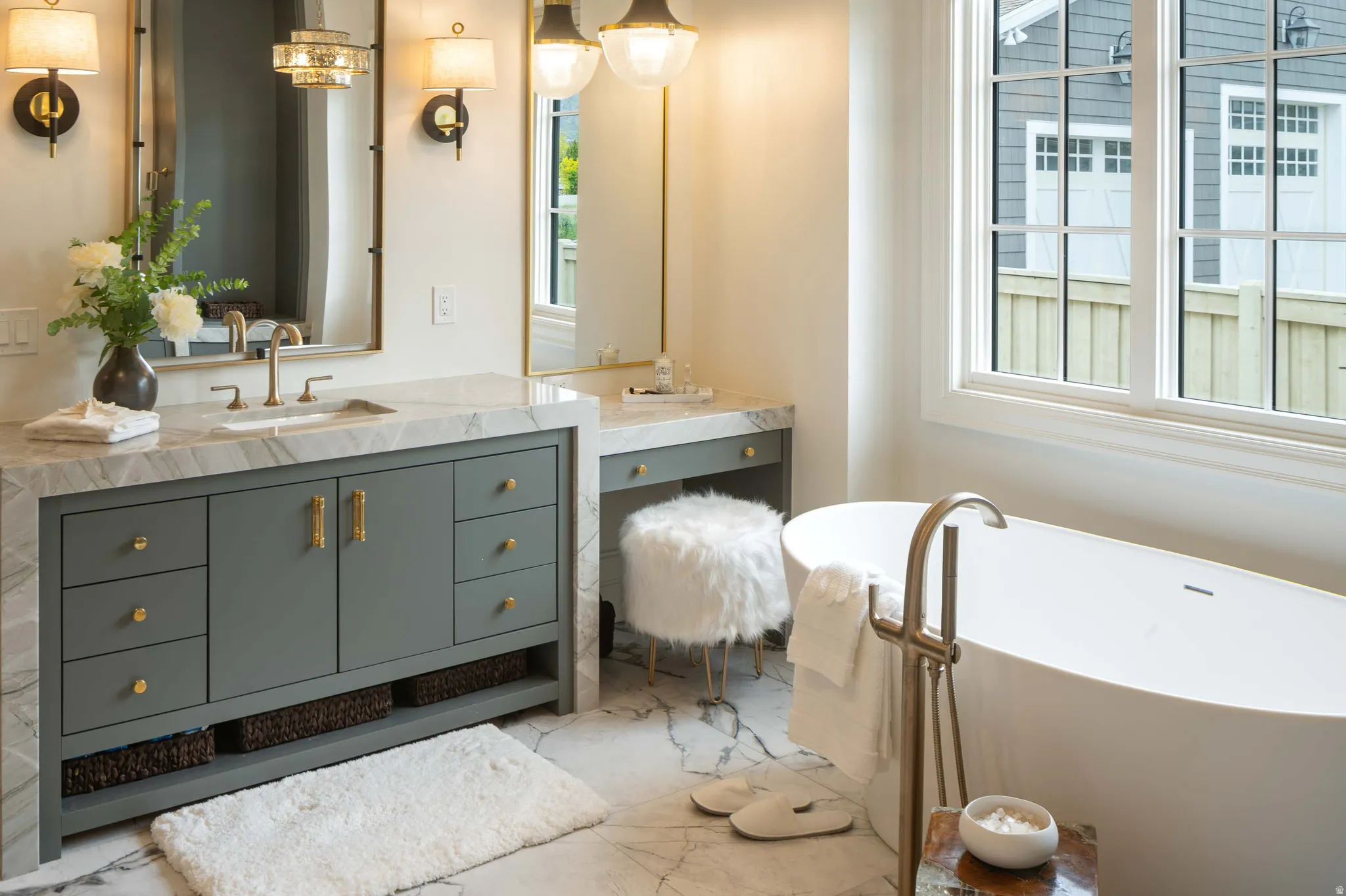 Bathroom featuring a freestanding soaking tub with a floor-mounted faucet, dual-pane windows, and marble-look flooring