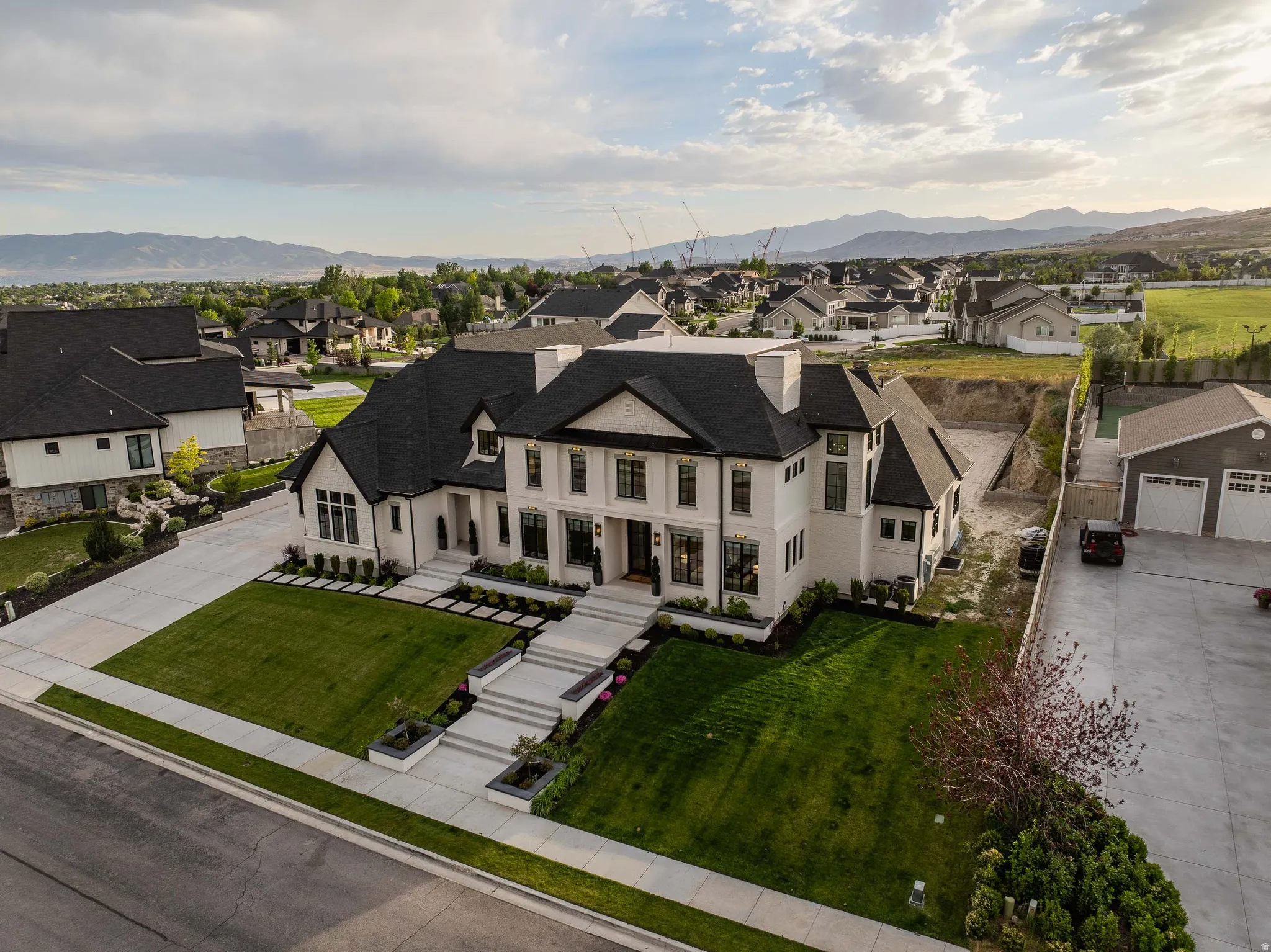 Stately residence featuring a white facade with black trim, multiple gables, and a dark shingle roof