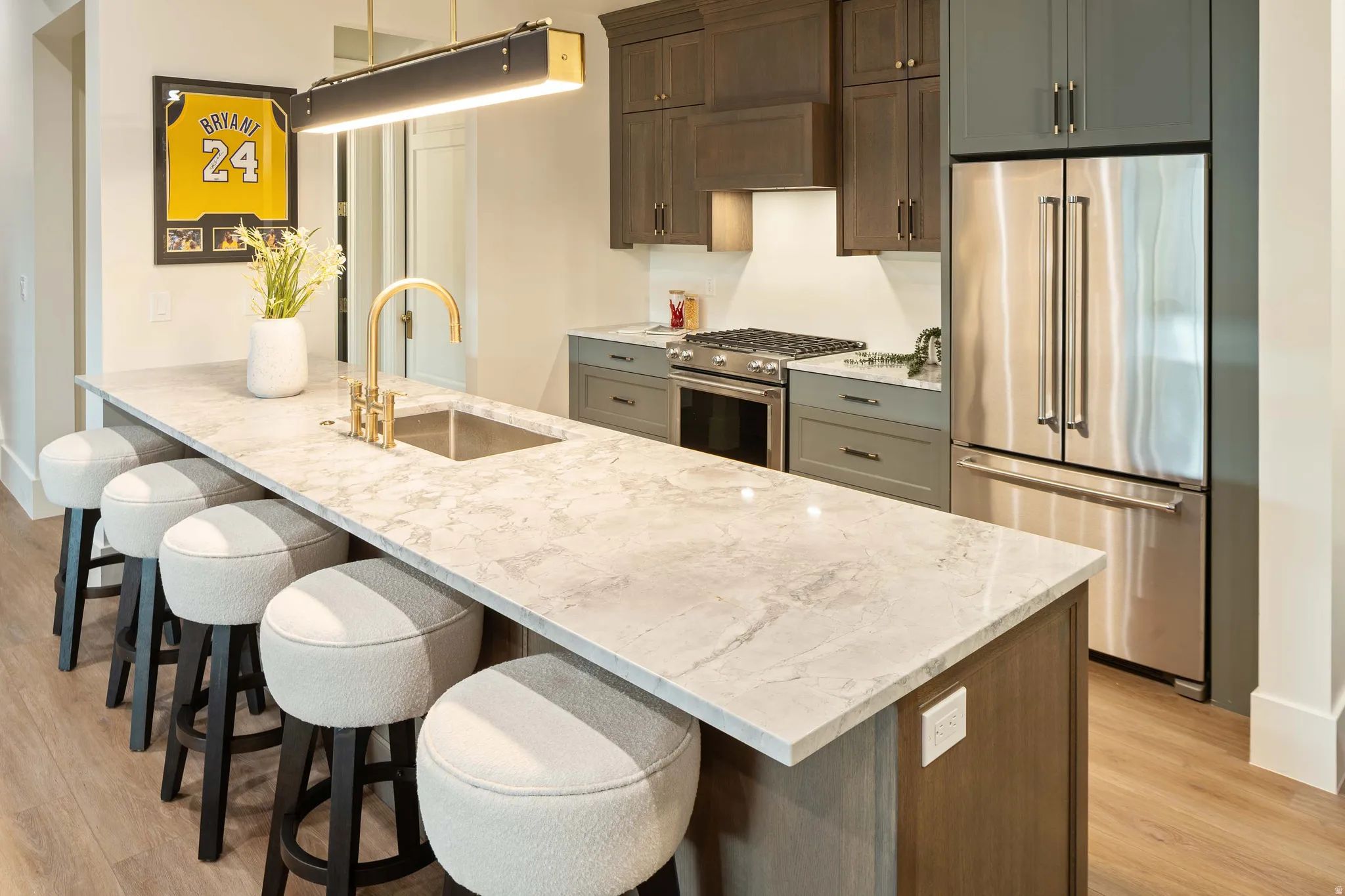 Central kitchen island featuring a light-toned countertop with an undermount sink and a gold-finish faucet