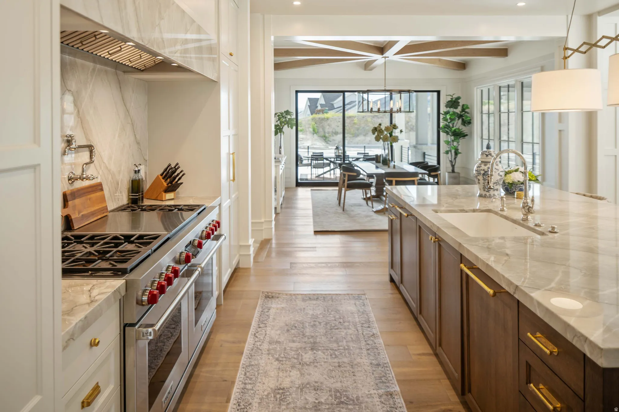 Gourmet kitchen featuring a professional-grade stainless steel range with a pot filler, a large center island with an undermount sink, and wood-finish flooring