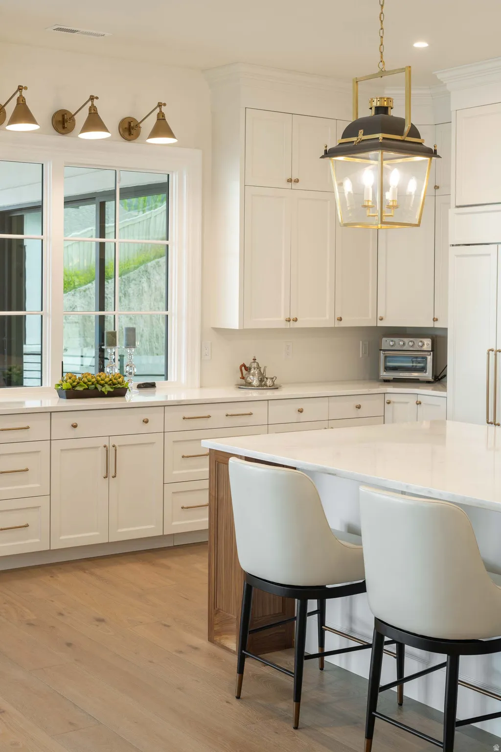 Gourmet kitchen with white cabinetry, light countertops, wood-finish flooring, a large center island, and a prominent lantern-style pendant light