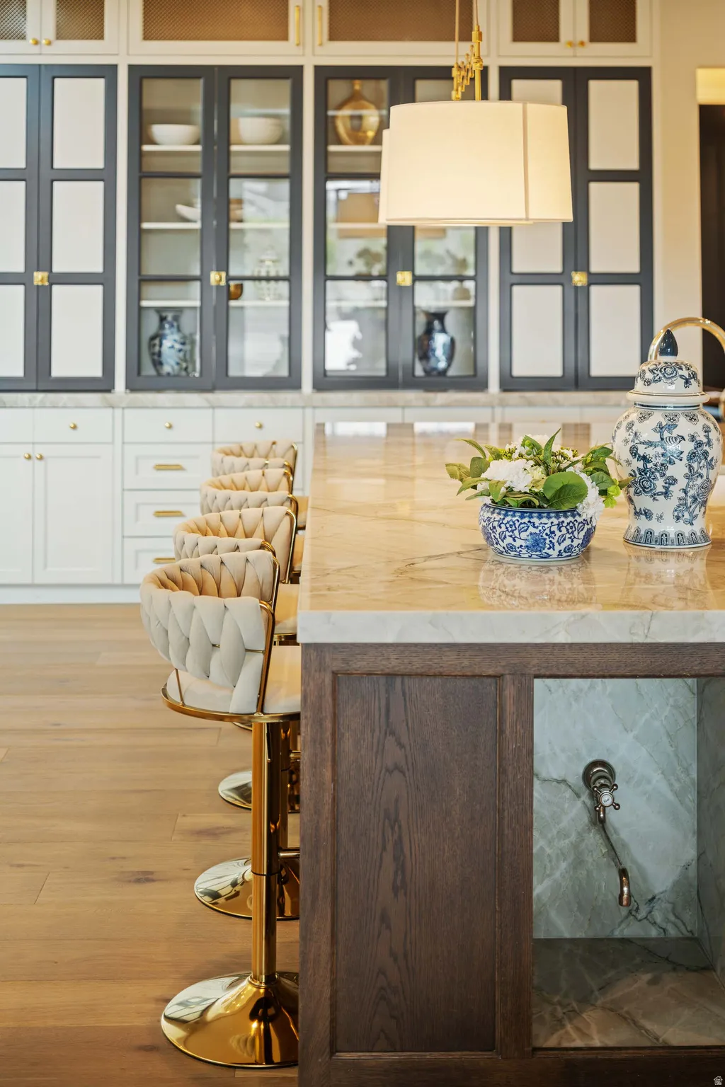 Kitchen island featuring a veined stone countertop, dark wood paneling, and an integrated stone sink with wall-mounted faucet