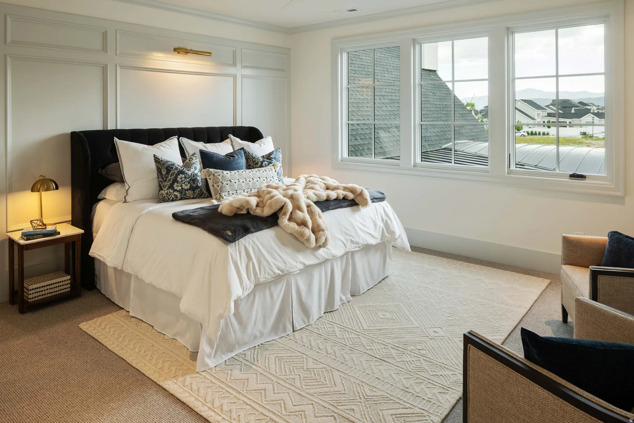 Wall paneling with integrated wall sconce lighting complements expansive windows showcasing a mountain backdrop